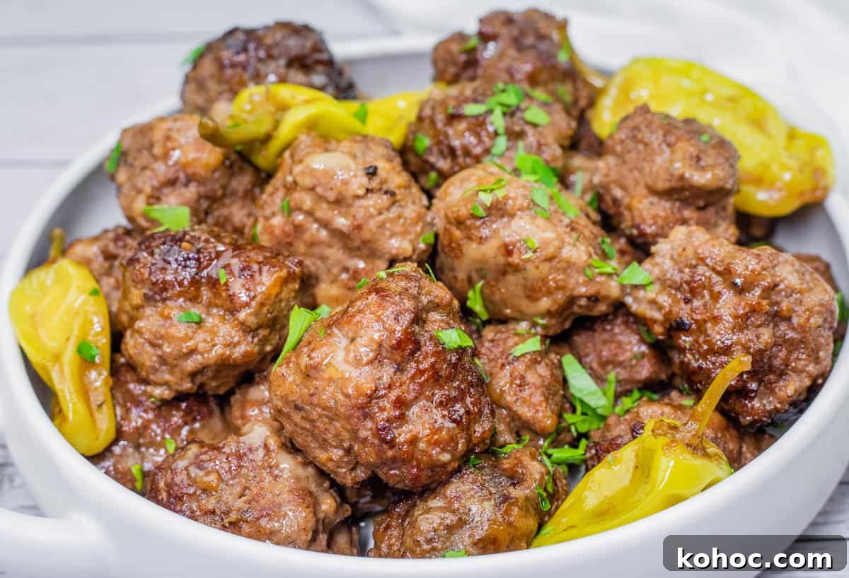 23 Dump-and-Go Slow Cooker Recipes That Taste Homemade 11 Bowl of browned Slow Cooker Mississippi Meatballs garnished with chopped parsley and yellow pepperoncini peppers.