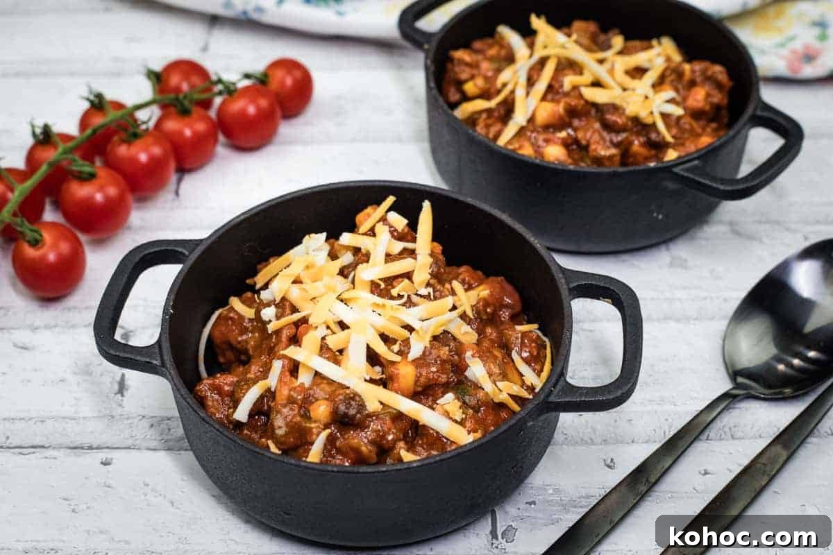 23 Dump-and-Go Slow Cooker Recipes That Taste Homemade 13 Two black pots of Slow Cooker Southwestern Chili topped with shredded cheese.