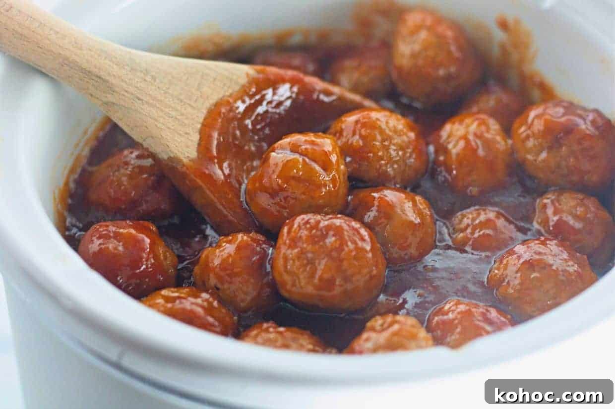 23 Dump-and-Go Slow Cooker Recipes That Taste Homemade 7 Honey-Garlic Meatballs in a thick red sauce are being stirred with a wooden spoon in a white ceramic pot.