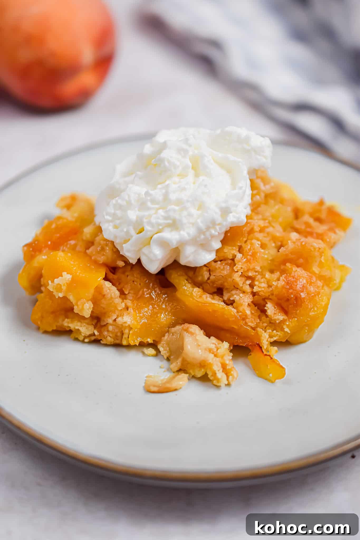 The peach cobbler is on a plate with whipped cream