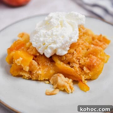 The peach cobbler is on a plate with whipped cream