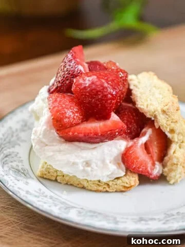 Strawberries are piled high on the whipped cream and biscuits.