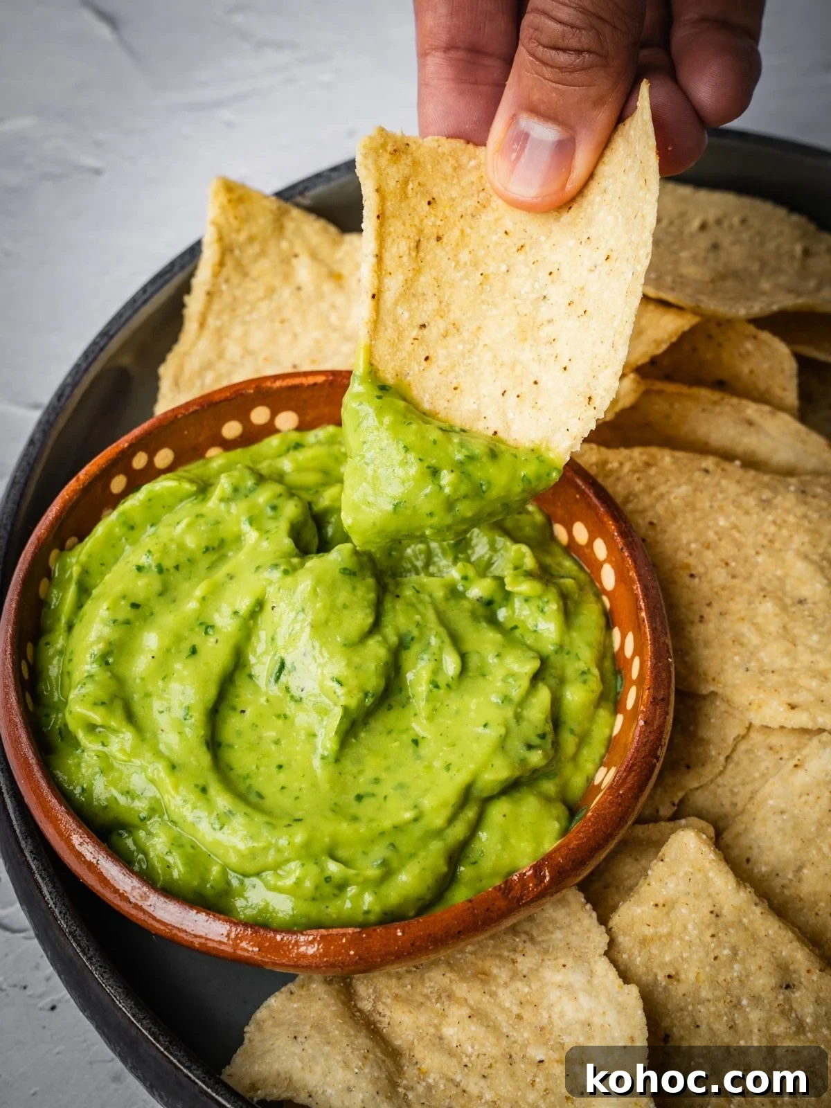 Dipping a nacho chip into the avocado salsa.