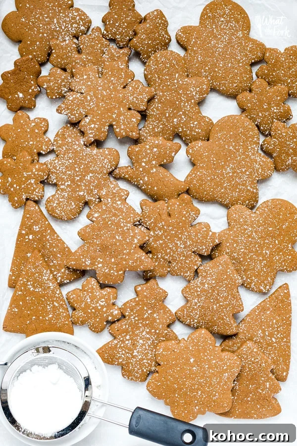 Gluten-Free Gingerbread Cookies Recipe for Perfect Holiday Bakes 8 overhead shot of gluten free gingerbread cookies on a parchment paper lined baking sheet dusted with powdered sugar