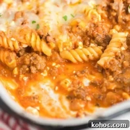One-Pot Creamy Tomato Basil Pasta for Quick Weeknight Meals 8 Side view of a cheesy baked lasagna casserole in a white dish, filled with pasta, meat sauce, and melted cheese.