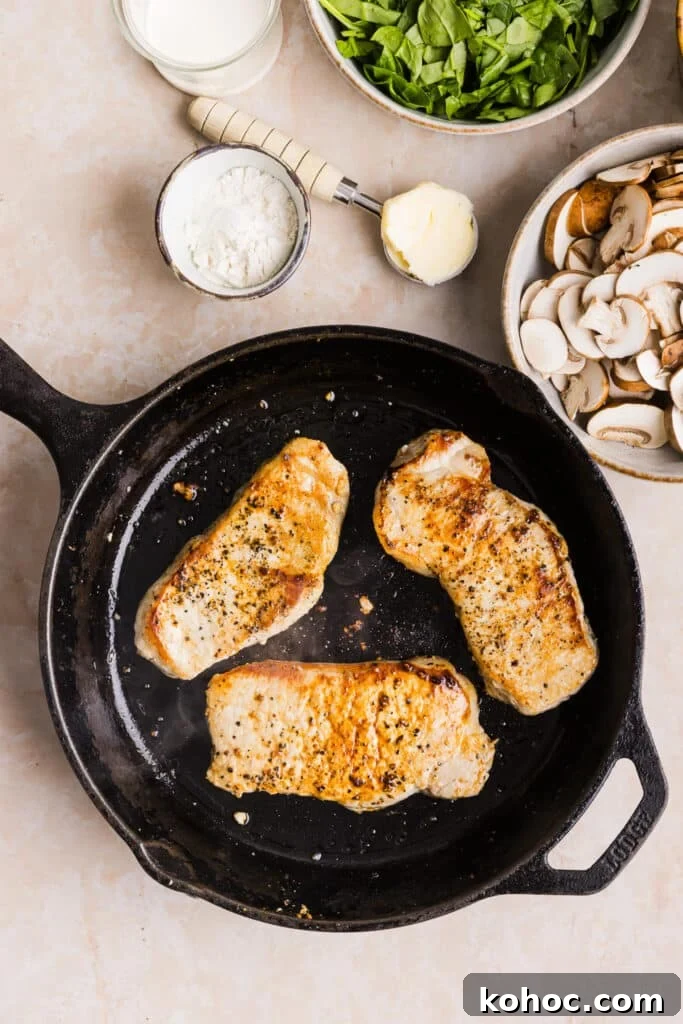 Creamy Garlic Pork Chops with Lighter Sauce 5 Pork chops being cooked and seared in a pan.