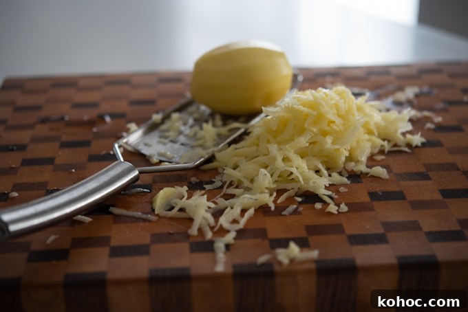 Cheesy Kimchi Potato Pancakes Recipe for Crispy, Flavorful Korean-Style Pancakes 4 Shredded potato on a cutting board.
