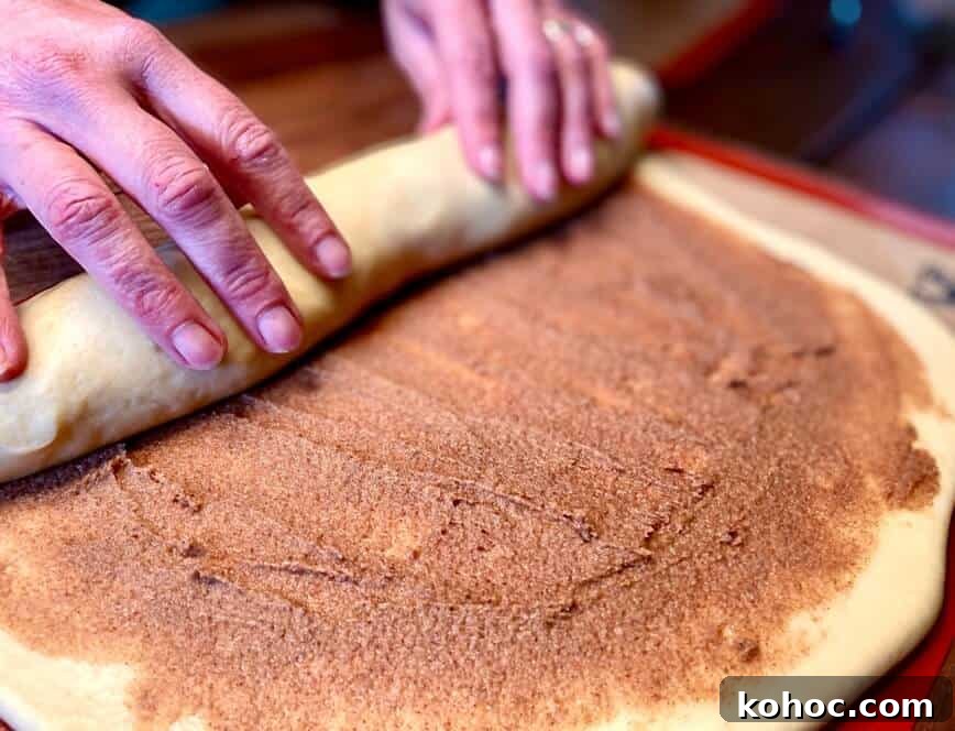 Soft Homemade Cinnamon Rolls with Cream Cheese Glaze 11 Rolling up the filled dough into a log shape.