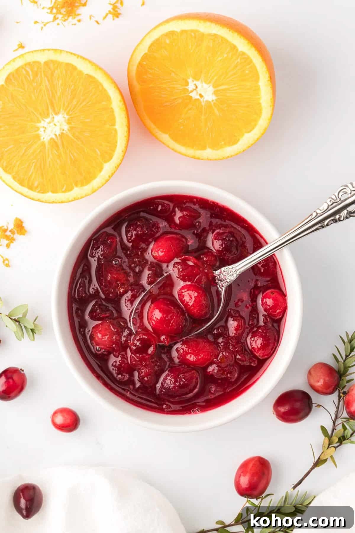 Overhead view of cranberry sauce in white ramekin with orange slices in the background.