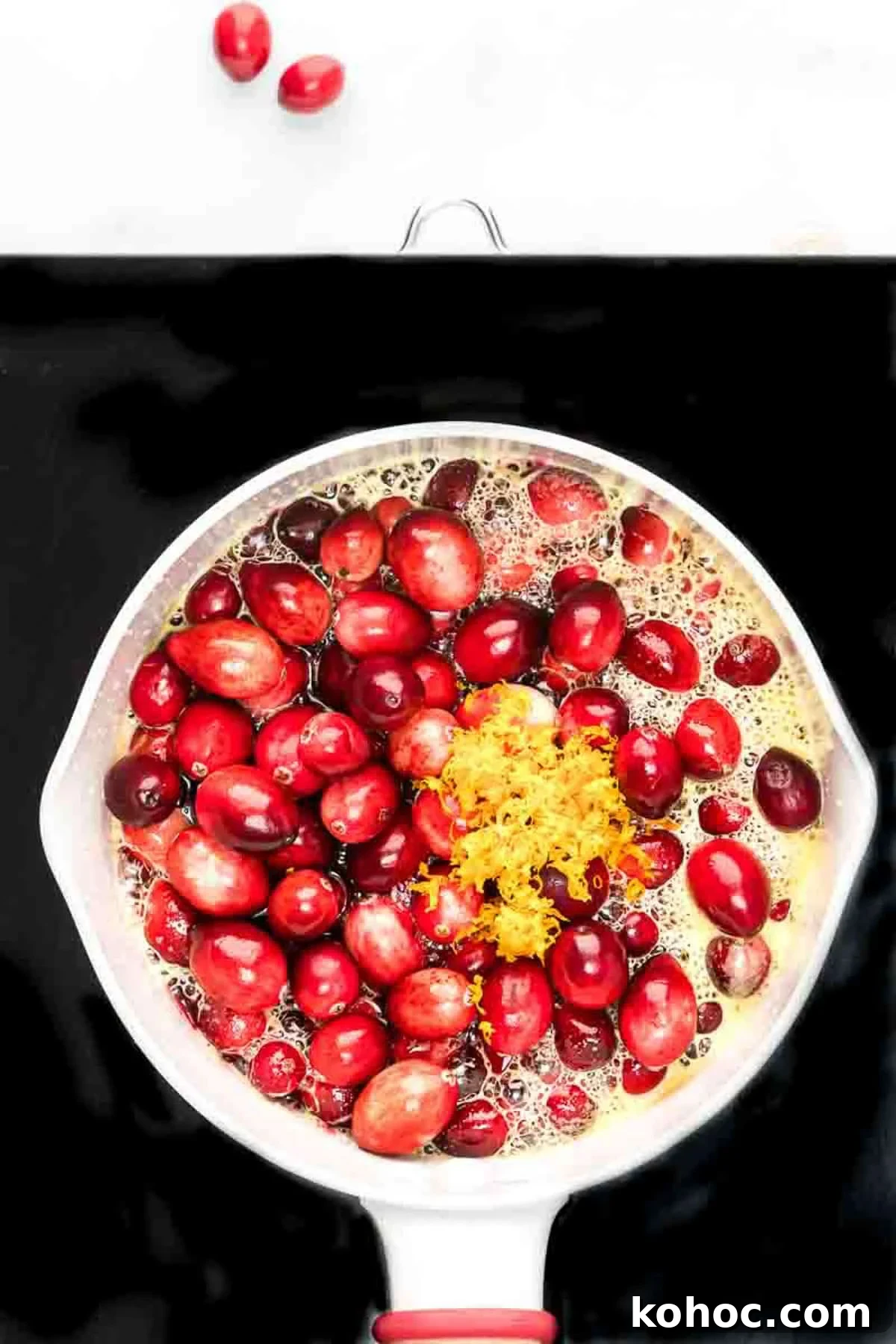 Overhead view of orange zest and cranberries added to pot