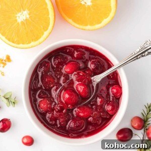 Overhead view of cranberry sauce in white ramekin with orange slices in the background.