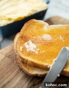 smudge of butter melting into slice of toast on chopping board