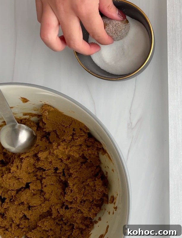 Crispy Gluten-Free Gingersnap Cookies You’ll Love 9 Cookie dough ball being rolled in granulated sugar.