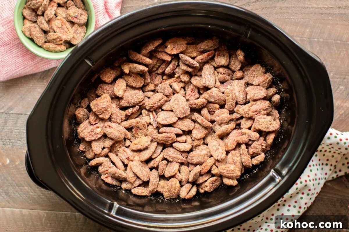 Perfectly Candied Pecans in the Slow Cooker (Simple Recipe) 6 full slow cooker of cooked candied pecans with polka dot napkin on the side.