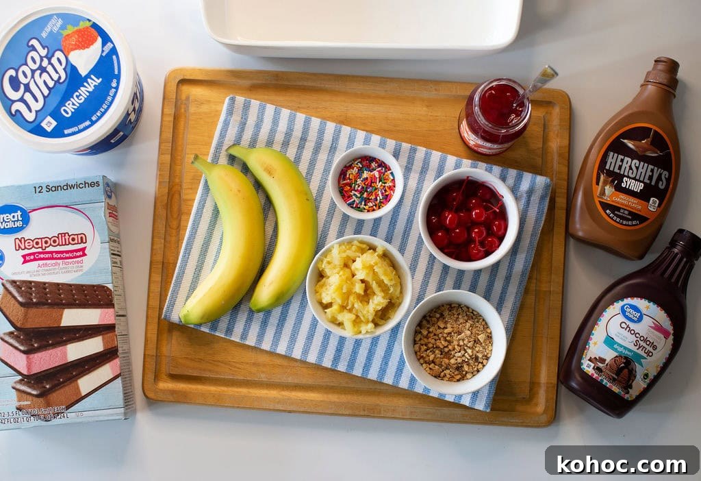 Banana Split Ice Cream Sandwich Cake Recipe for Summer Parties 5 A wooden tray holds two bananas, bowls of pineapple, cherries, nuts, sprinkles, and a jar of strawberry topping on a striped cloth. Surrounding the tray are ice cream sandwiches, whipped topping, and chocolate syrups.