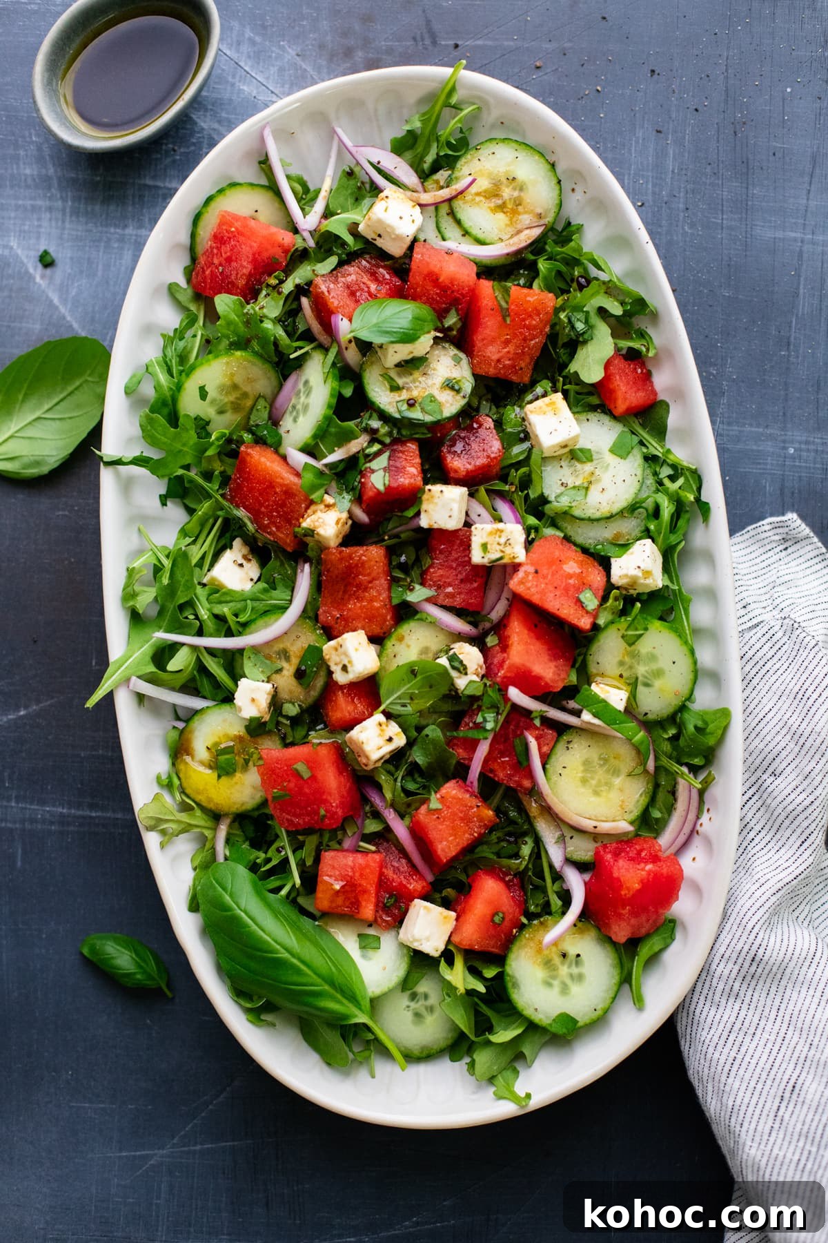 Watermelon, Feta & Basil Salad with Balsamic Glaze 2 watermelon feta salad on a oval white plate on gray background with white napkin next to it.