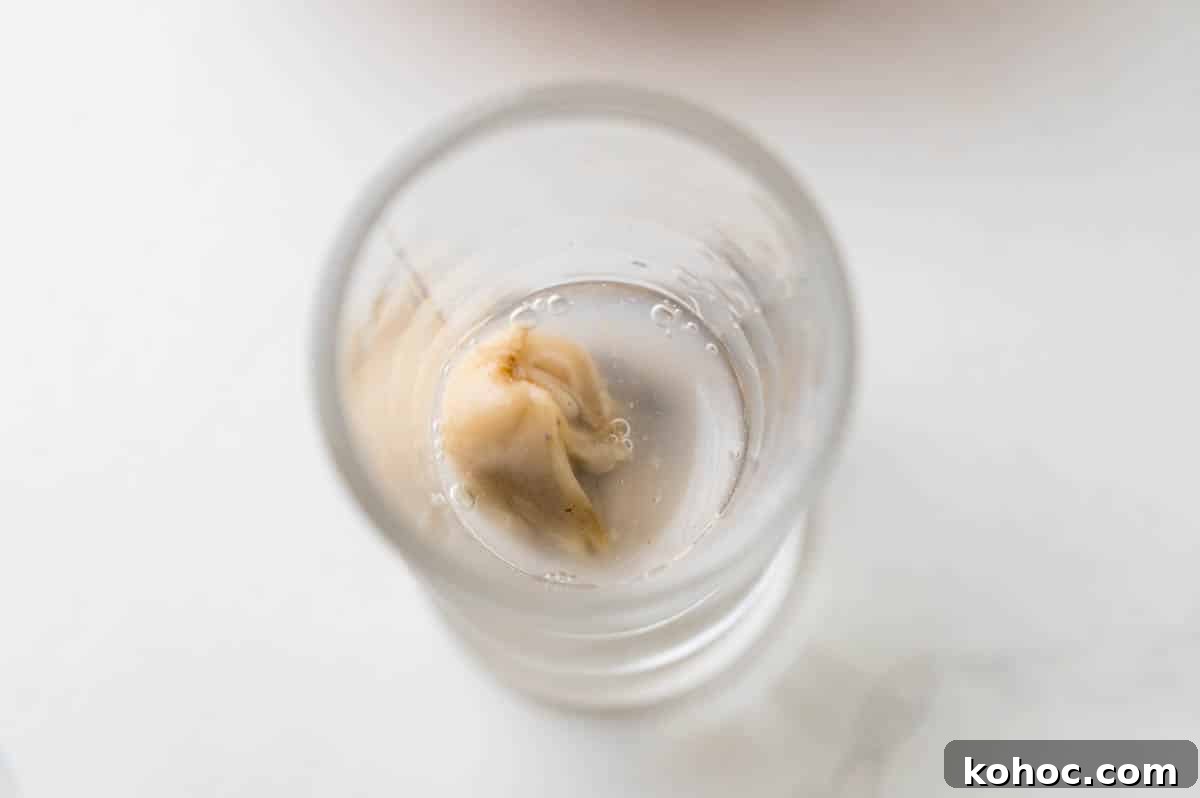 Adding an oyster and its liqueur to a shot glass.