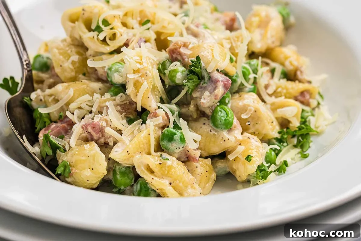 29 Tasty Meals You Can Make with Frozen Vegetables 2 A plate of creamy pancetta pea pasta with chunks of ham, garnished with parsley and grated cheese, served with a fork.