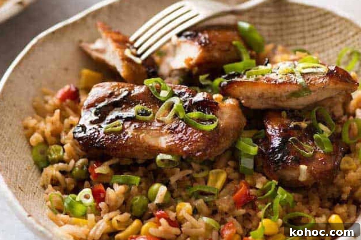 29 Tasty Meals You Can Make with Frozen Vegetables 15 Plate of grilled chicken thighs on a bed of fried rice using frozen vegetables, garnished with chopped green onions, served with a fork.