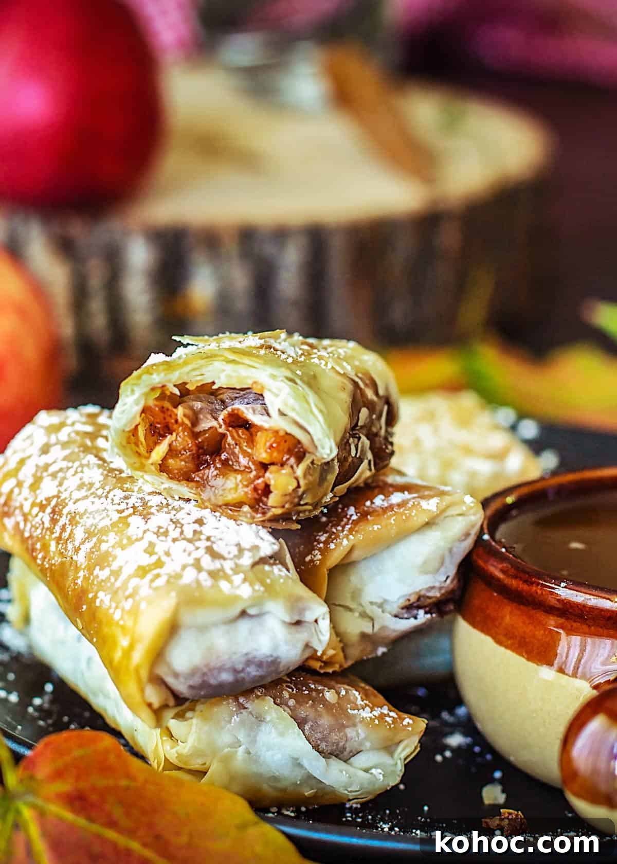 Crispy Apple Pie Spring Rolls with Filo Pastry 10 Stacked apple pie filo rolls with the top one split in half to reveal the filling.