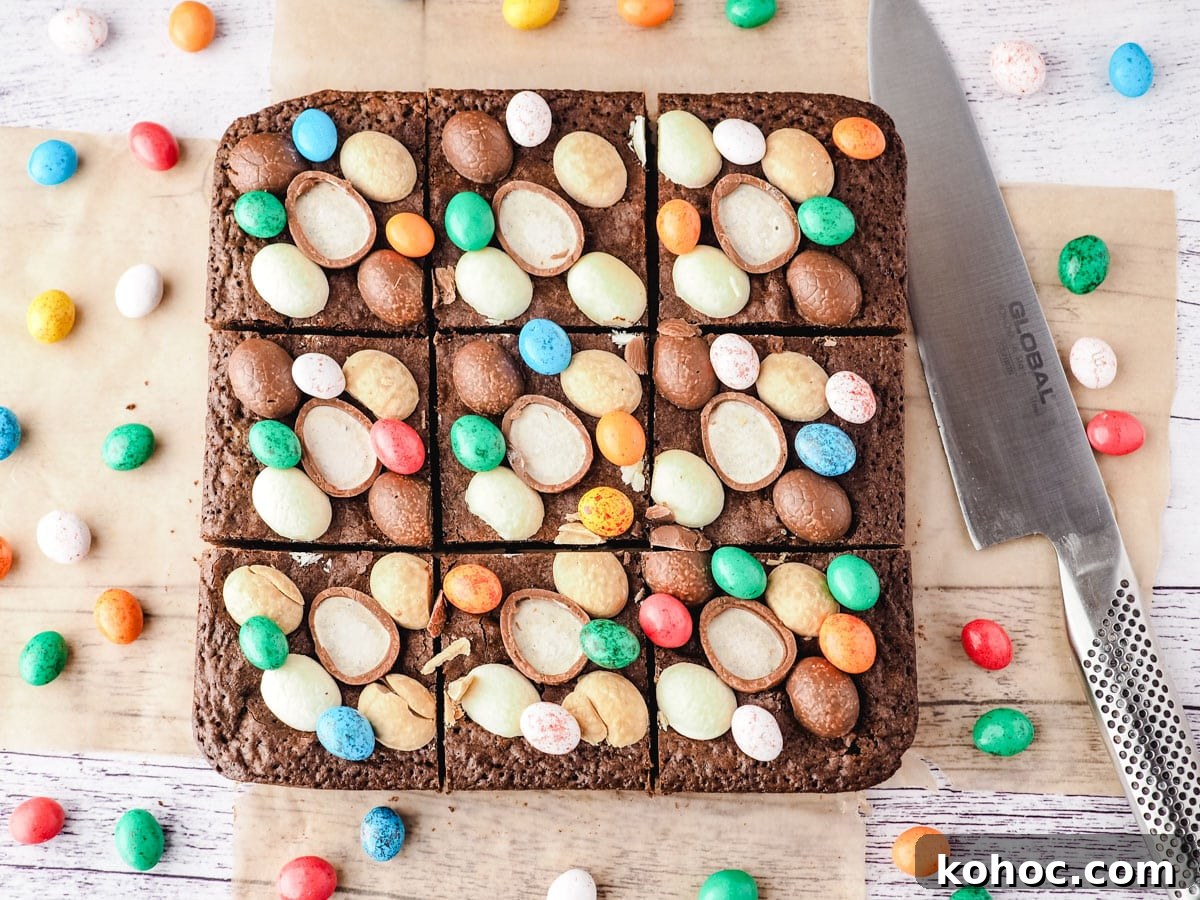 Top down shot of sliced Easter brownies with a knife on the side, surrounded by extra Easter eggs.