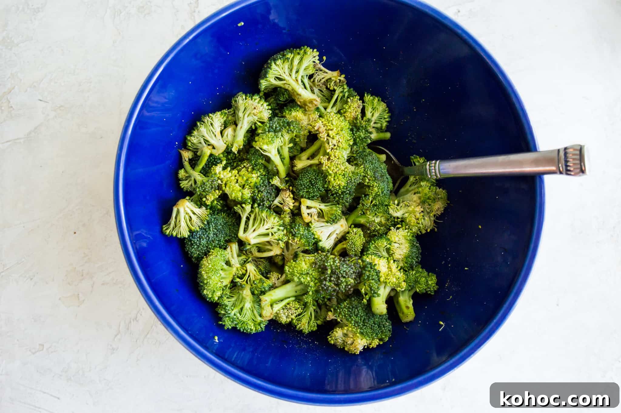Crispy Air Fryer Broccoli Recipe in 15 Minutes 4 A bowl with broccoli florets in it with a spoon in the bowl.