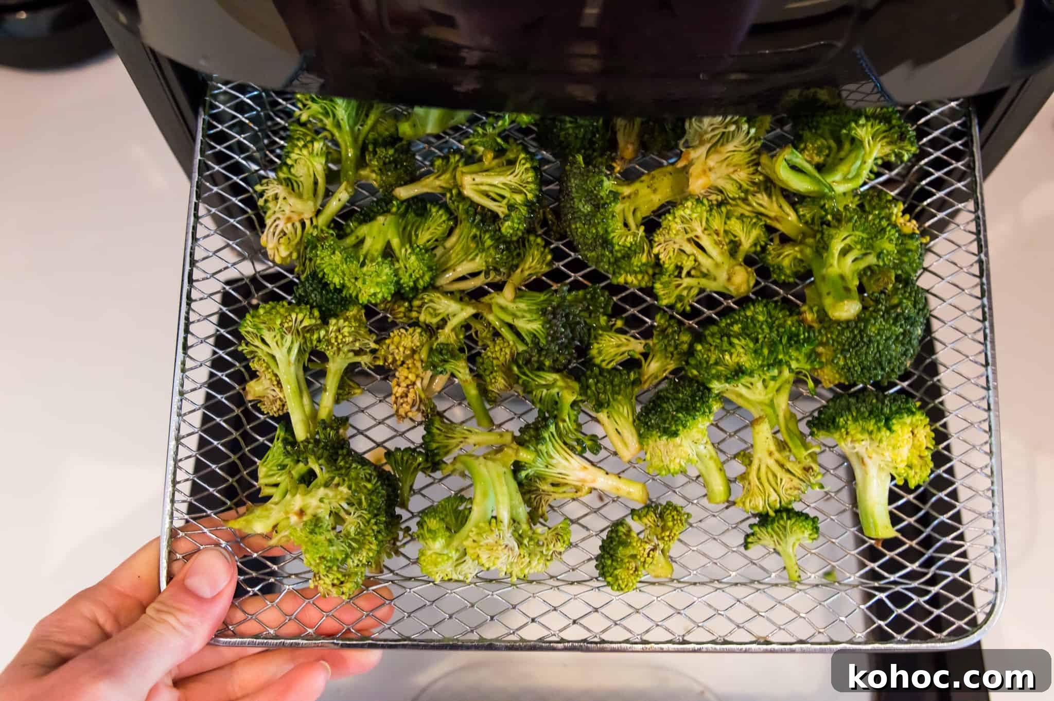 Crispy Air Fryer Broccoli Recipe in 15 Minutes 5 Broccoli florets on an air fryer tray.