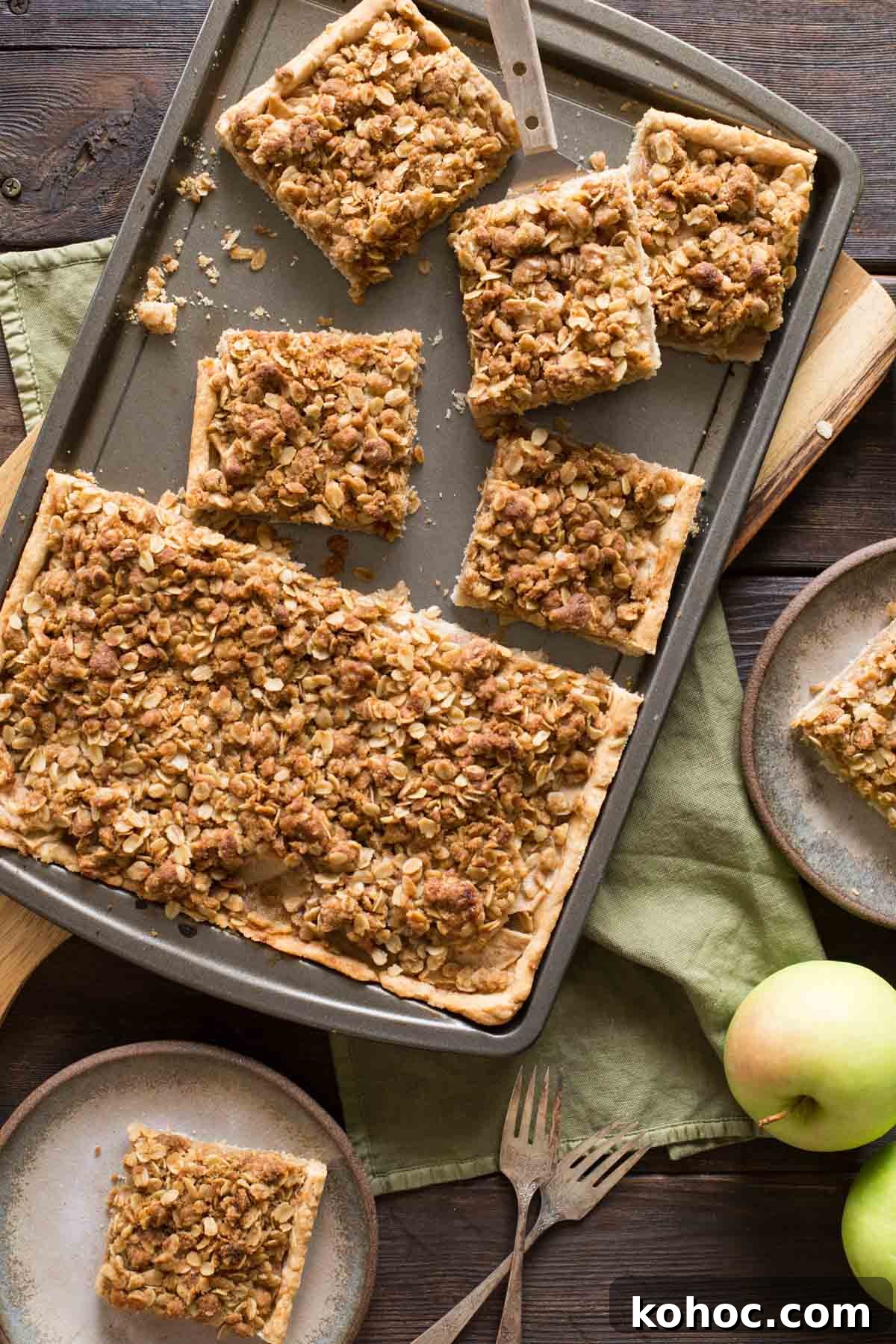 A top down view of a Dutch Apple Slab Pie with a few pieces cut out and fresh apples scattered around. 