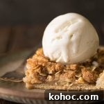 A close up view a piece of Dutch Apple Slab Pie with a scoop of vanilla ice cream on top.