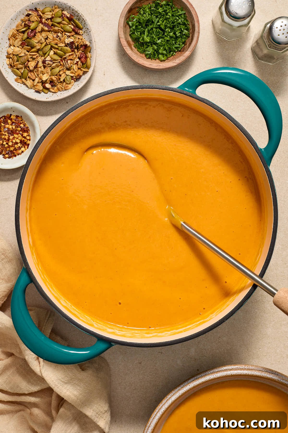 Roasted Red Pepper & Butternut Squash Soup — Dairy-Free Vegan Recipe 9 Soup warmed in a large pot with a ladle and soup toppings surrounding the pot.