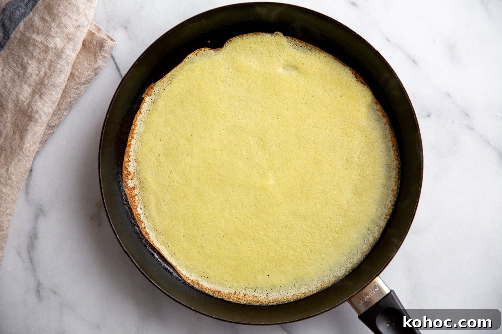 Process shot showing a crepe cooking in a non-stick skillet. 