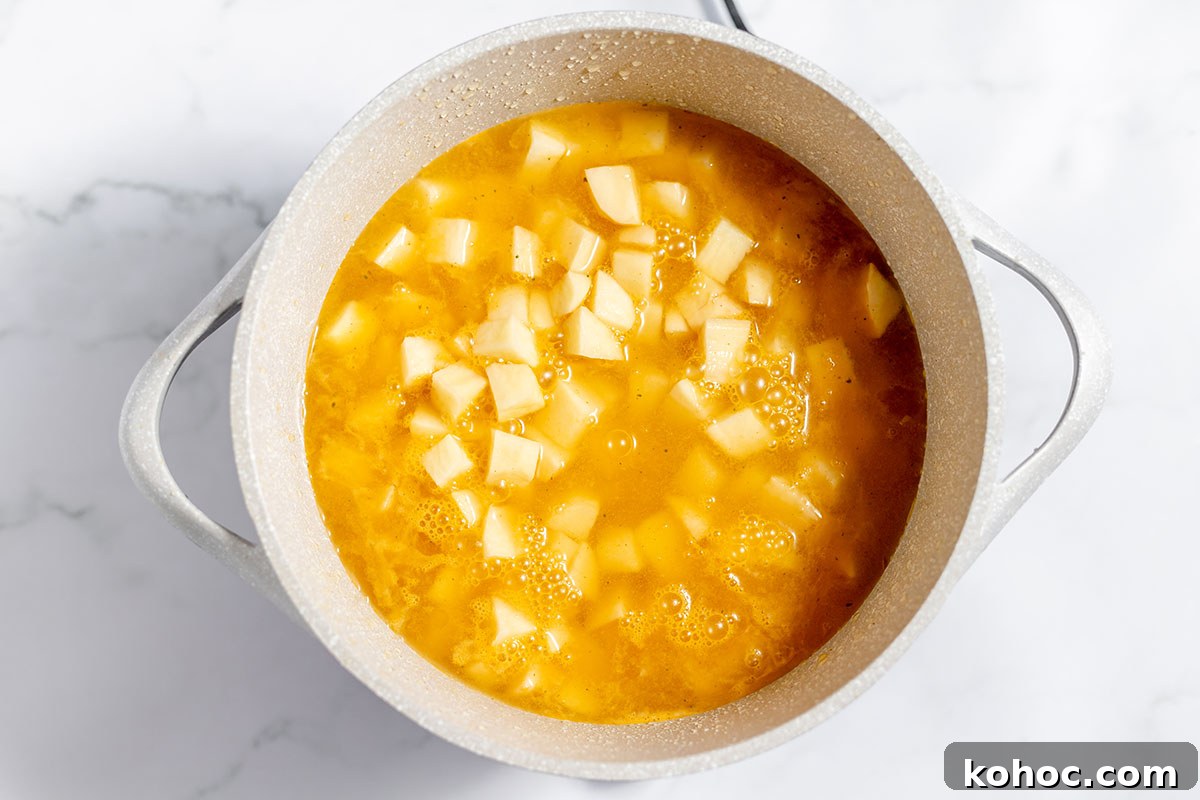 Creamy Baked Potato Soup with Crispy Bacon Topping 4 Potatoes and chicken broth in a stock pot.