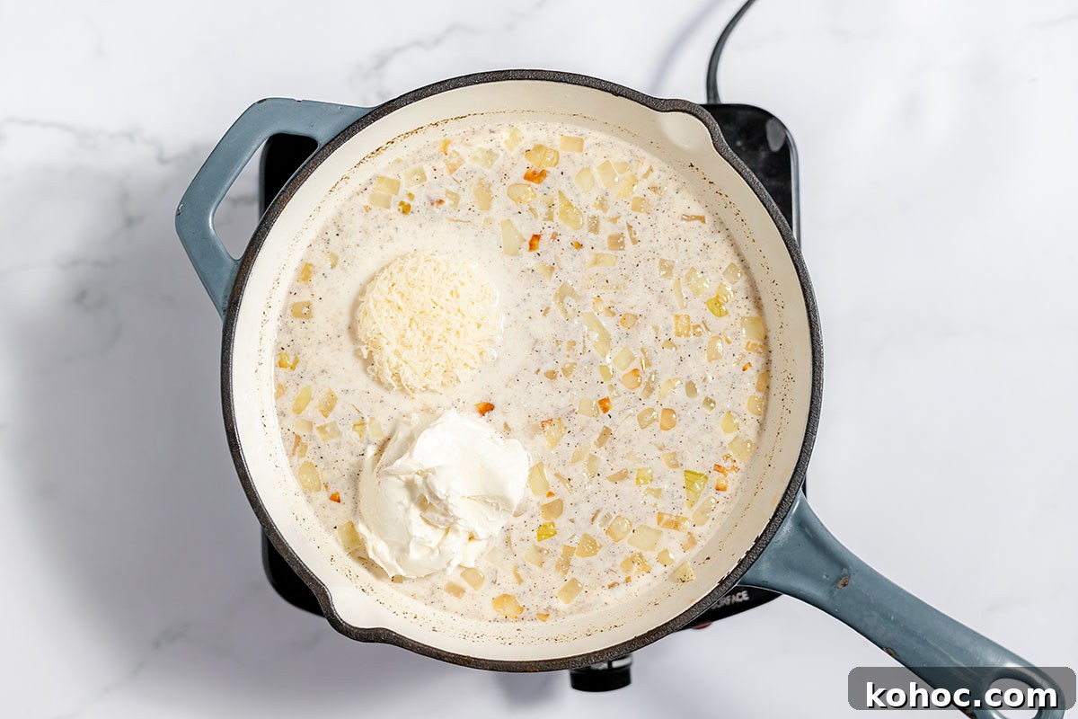 Creamy Baked Potato Soup with Crispy Bacon Topping 6 Cream cheese and Parmesan cheese are added to the onion and milk mixture in the skillet.