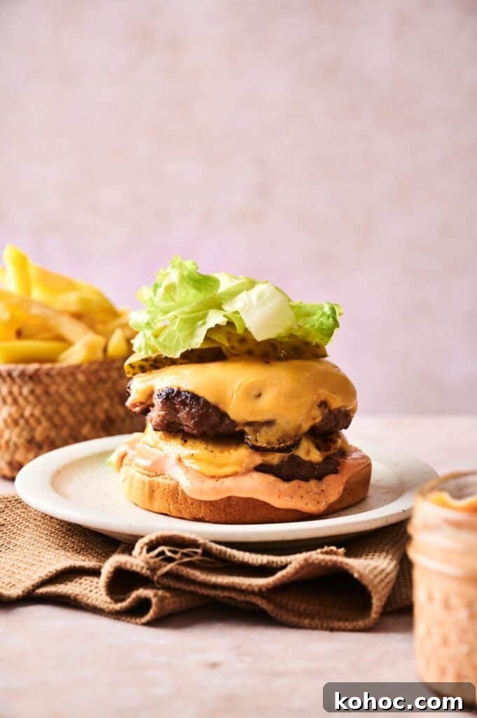 Savvy Slider Copycat Recipe: How to Make Restaurant-Style Sliders 6 A Copycat Savvy Slider cheeseburger with lettuce, pickles, and sauce on a bun sits on a white plate, served with French fries in the background.