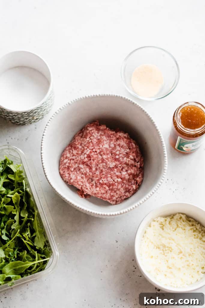 Juicy Lucy Lamb Burger Recipe: Melted Cheese Inside Every Bite 3 Ingredients for the burgers set out on a surface - salt, garlic powder, a jar of fig preserves, arugula, lamb meat, and mozzarella