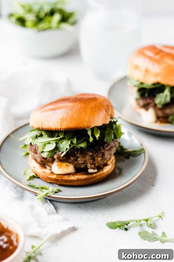 Juicy Lucy Lamb Burger Recipe: Melted Cheese Inside Every Bite 4 A lamb burger topped with arugula and fig preserves, in a brioche bun, on a blue plate