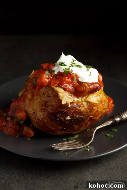 Slow Cooker Baked Jacket Potatoes Recipe 10 A slow cooker jacket potato on a grey plate topped with vegan chilli and vegan creme fraiche