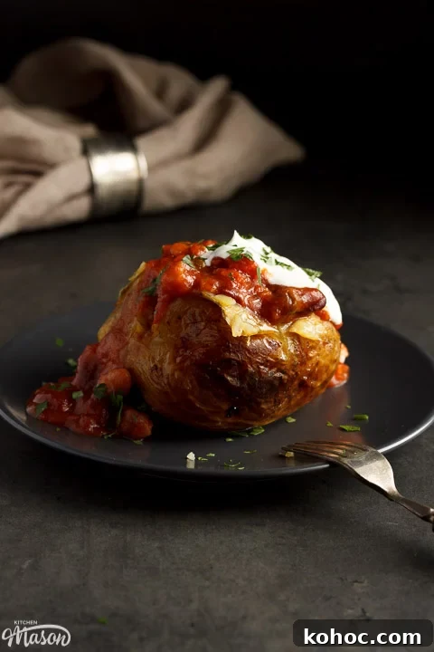Slow Cooker Baked Jacket Potatoes Recipe 2 A slow cooker jacket potato on a grey plate topped with vegan chilli and vegan creme fraiche