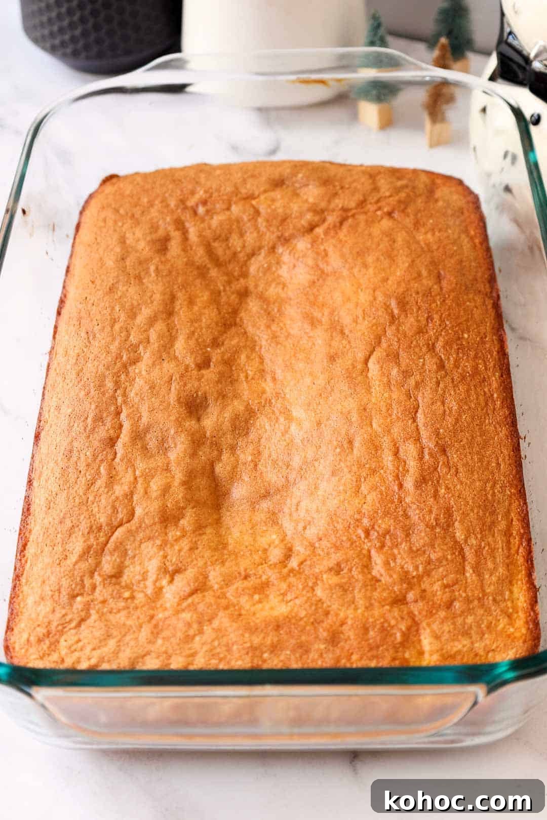 A golden-baked butter cake layer cooling in a glass baking dish.