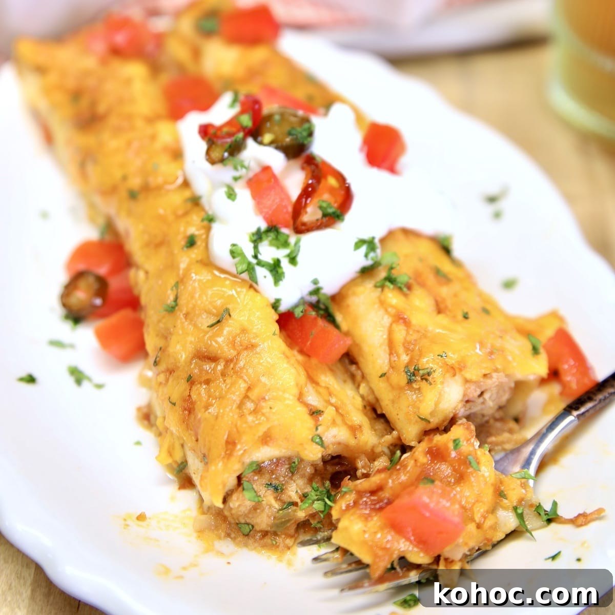 Slow-Cooker Pulled Pork Casserole with Cheesy Topping 10 Pulled pork enchiladas on a plate with sour cream and tomatoes.