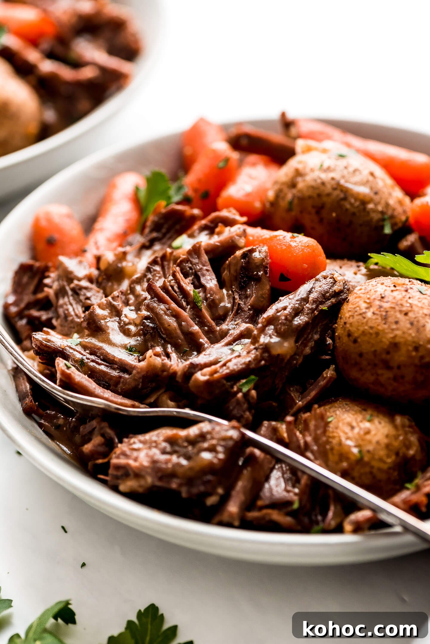 Juicy Instant Pot Pot Roast Recipe for Tender, Quick Dinner 3 Pot Roast in a bowl with potatoes, and carrots, and drizzled with brown gravy.