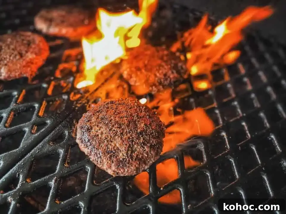 hamburgers on a pitboss pellet grill with flames searing them to perfection