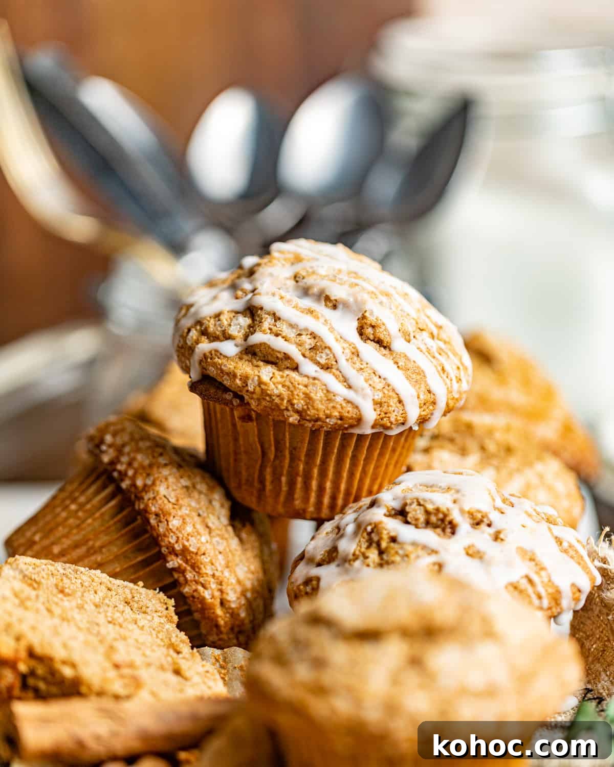 Gingerbread Muffins with Molasses Glaze: Cozy Holiday Treats 5 gingerbread muffins stacked on top of one another in front of a jar of spoons.
