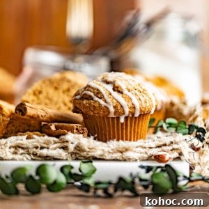 Gingerbread Muffins with Molasses Glaze: Cozy Holiday Treats 10 gingerbread muffins on a wood surface with a maple glaze drizzle on top.