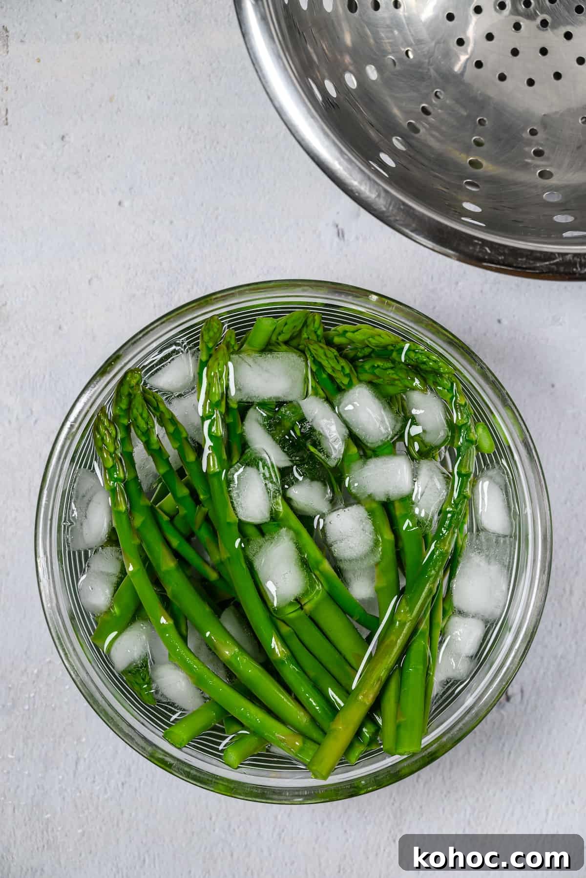 Blanched asparagus in a bowl of ice water.