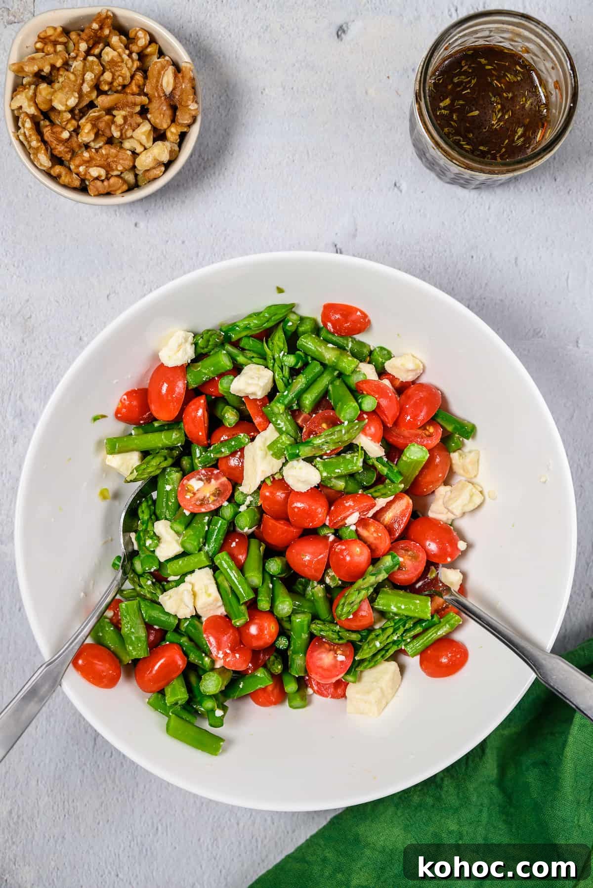 Assembled asparagus salad with serving utensils.