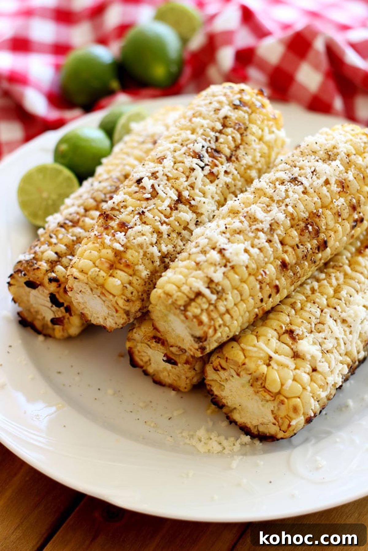 22 Memorial Day Recipes for the Ultimate Backyard BBQ 13 A plate of five grilled corn on the cobs covered with cotija cheese on a white plate.