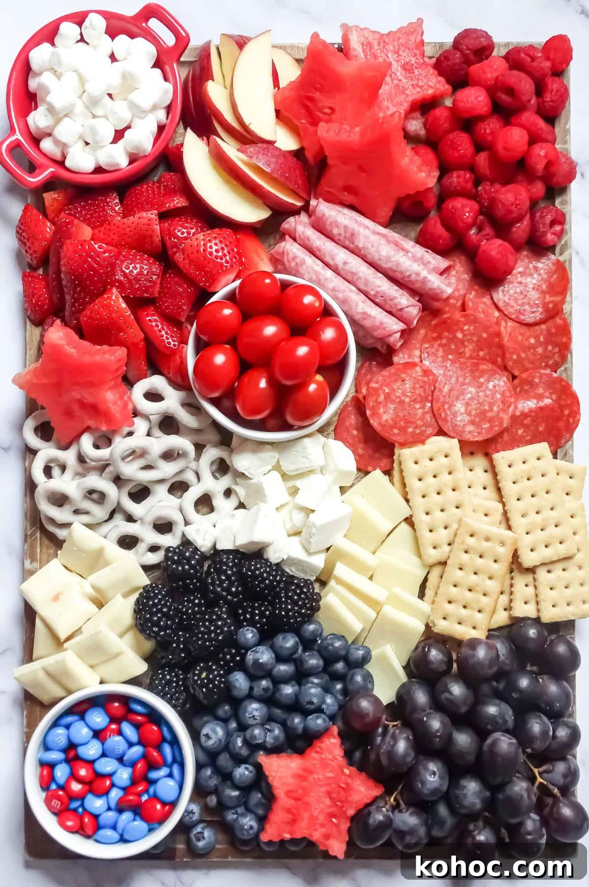 22 Memorial Day Recipes for the Ultimate Backyard BBQ 3 Fruit, pretzels, cheese, crackers, salami, and apples on a board being served as an appetizer.