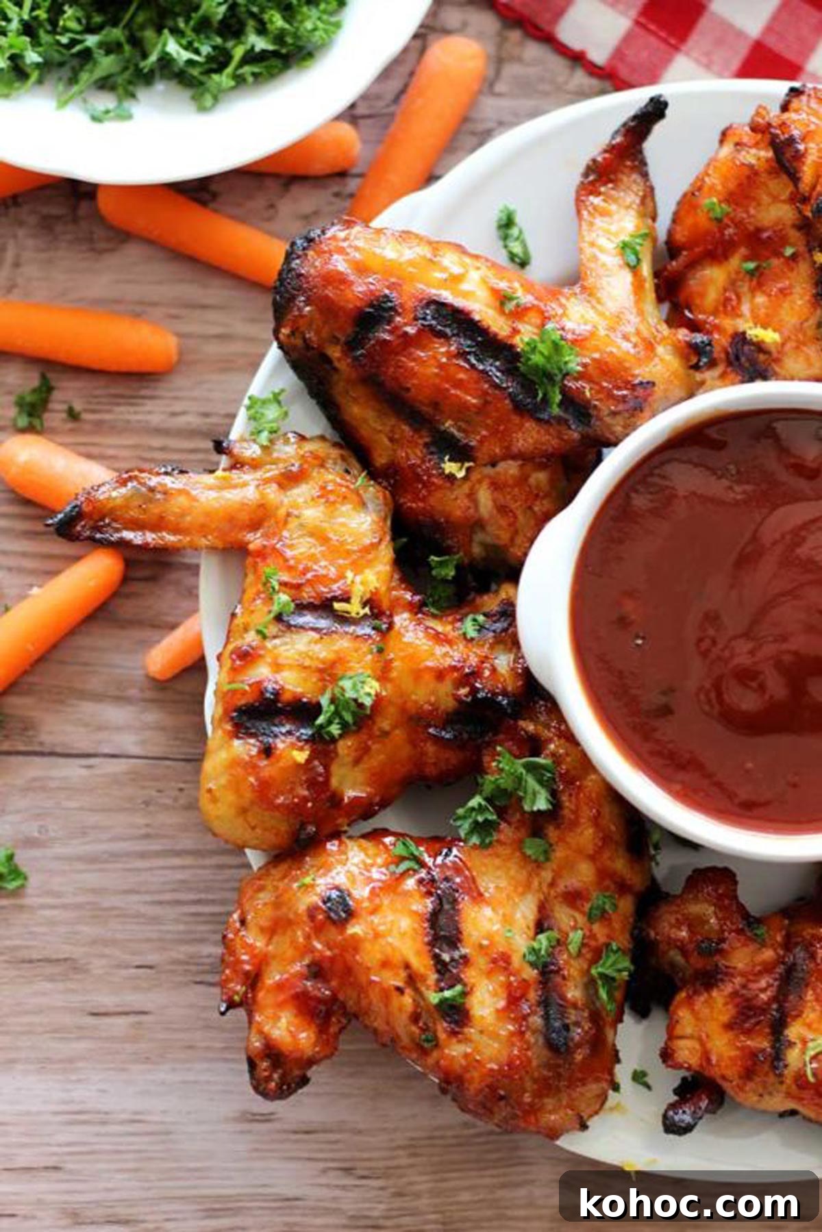 22 Memorial Day Recipes for the Ultimate Backyard BBQ 4 BBQ chicken wings on a white serving plate with dipping sauce.
