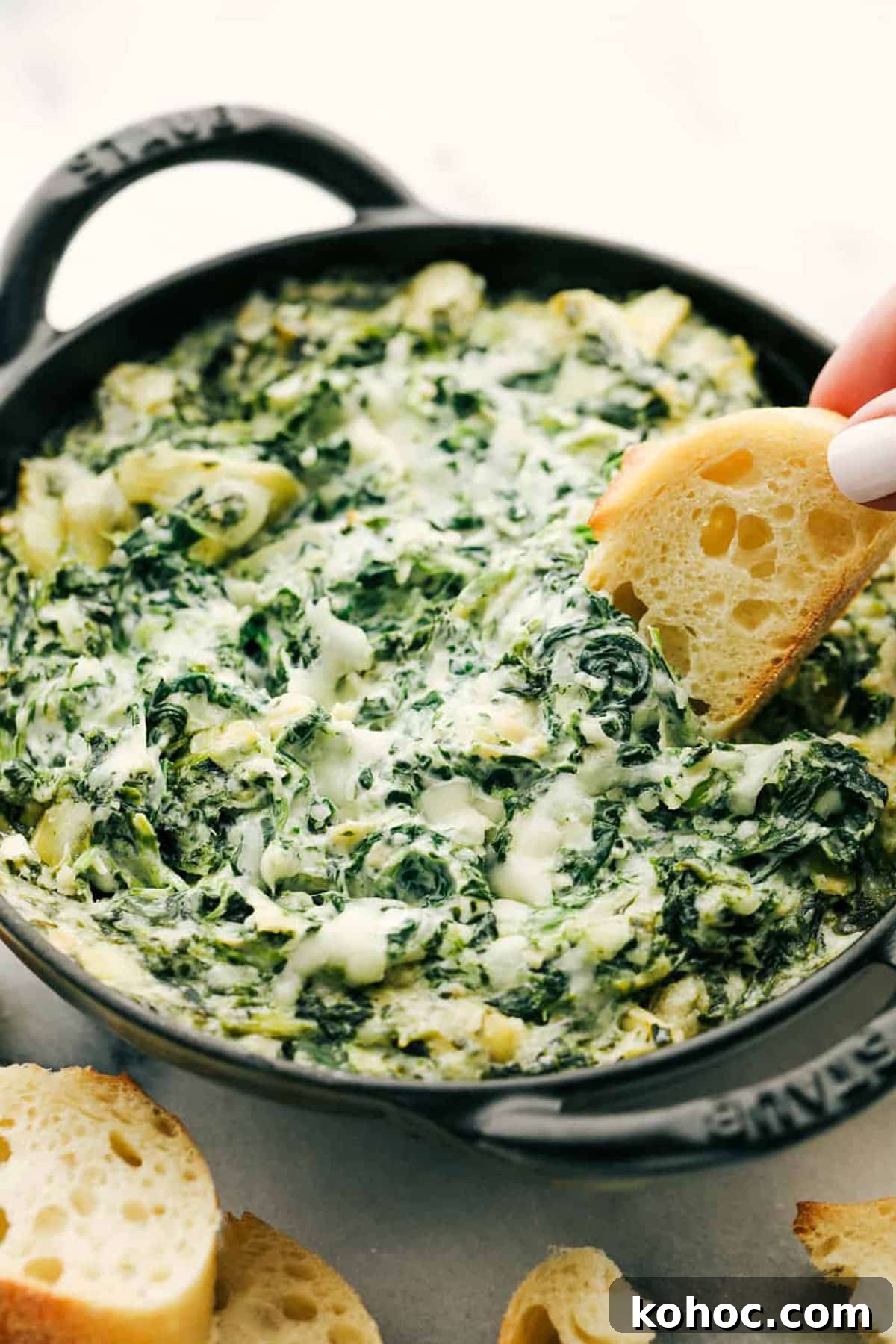22 Memorial Day Recipes for the Ultimate Backyard BBQ 5 Spinach and artichoke dip in a cast iron skillet, baguette being dipped into dip.